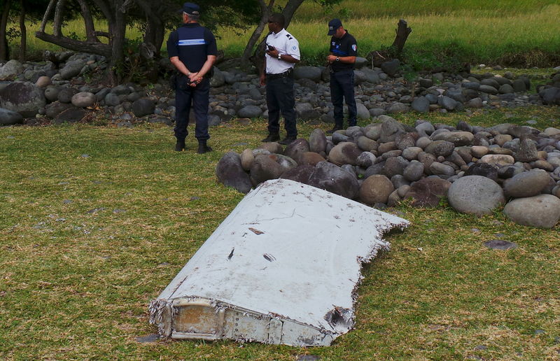 © Reuters. French gendarmes and police stand near a large piece of plane debris which was found on the beach in Saint-Andre, on the French Indian Ocean island of La Reunion