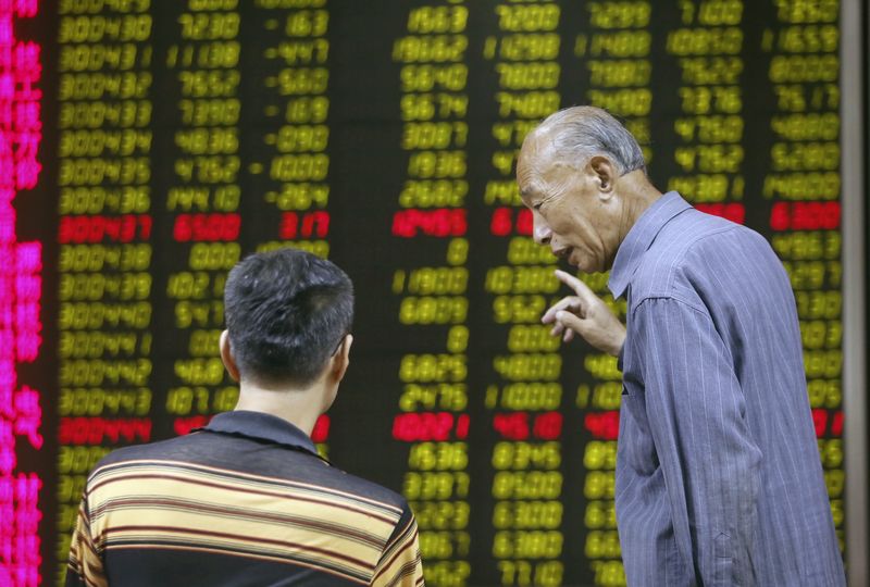 © Reuters. Investors talk in front of an electronic board showing stock information at a brokerage house in Beijing