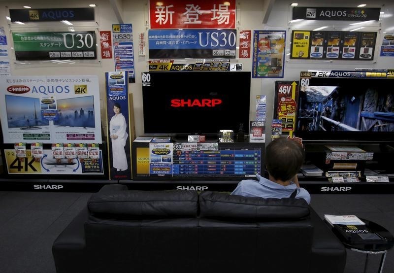 © Reuters. A man sitting on a sofa looks at a Sharp Corp's Aquos TV at an electronics retailer in Tokyo