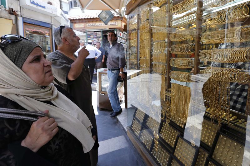 © Reuters. Customers look at gold jewellery displayed at a shop in Amman