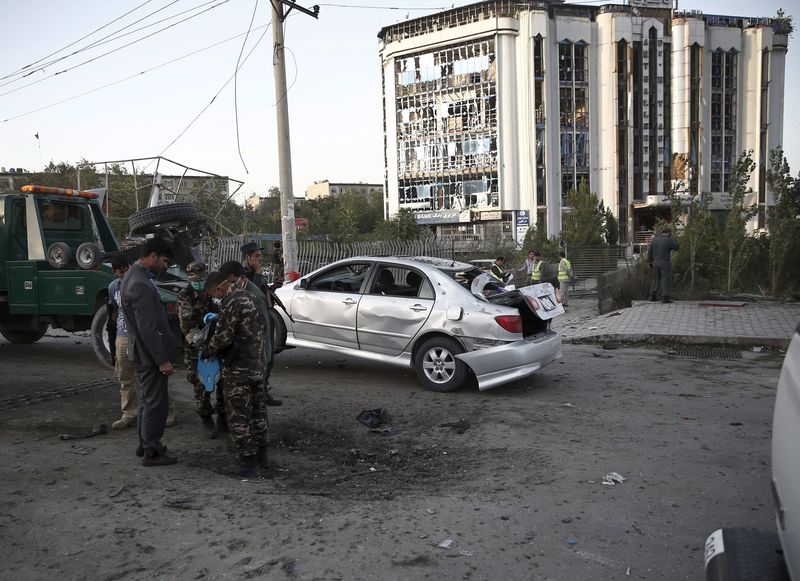 © Reuters. A damaged car is moved away from a crater caused by a car bomb blast in Kabul, Afghanistan 