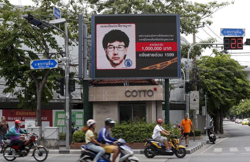 © Reuters. People ride their motorcycles past a digital billboard showing a sketch of the main suspect in Monday's attack on Erawan shrine, in Bangkok, Thailand