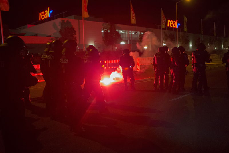 © Reuters. Policemen stand between flares thrown by right wing protesters who are against bringing asylum seekers to an accomodation facility in Heidenau