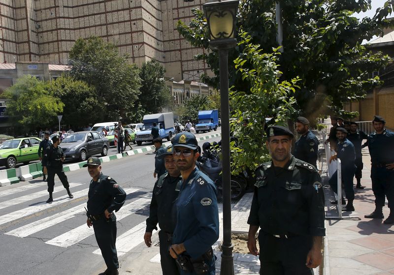 © Reuters. Police officers watch as convoy carrying members of British media leaves British Embassy in Tehran