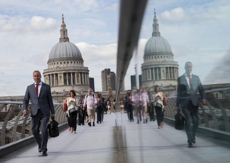 © Reuters. Commuters cross the Millennium Bridge in London