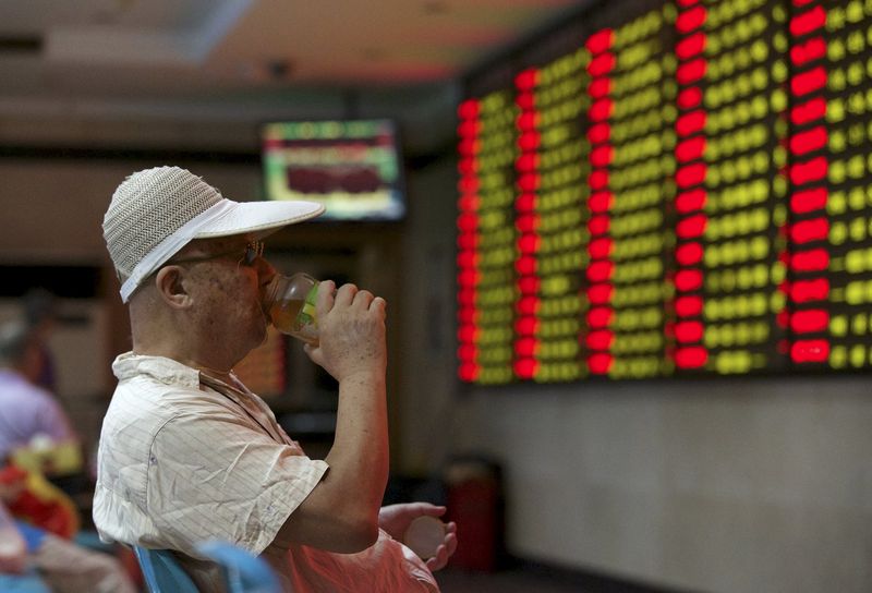 © Reuters. An investor drinks from a bottle as he looks at an electronic board showing stock information at a brokerage house in Nanjing