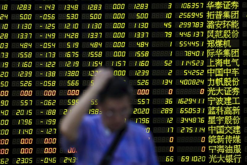 © Reuters. An investor stands in front of electronic board showing stock information at brokerage house in Shanghai