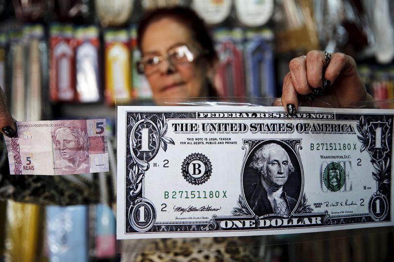 © Reuters. Mulher segura nota gigante de dólar e uma nota de 5 reais em Itu