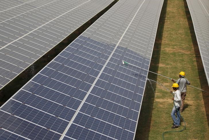 © Reuters. Workers clean photovoltaic panels inside a solar power plant in Gujarat