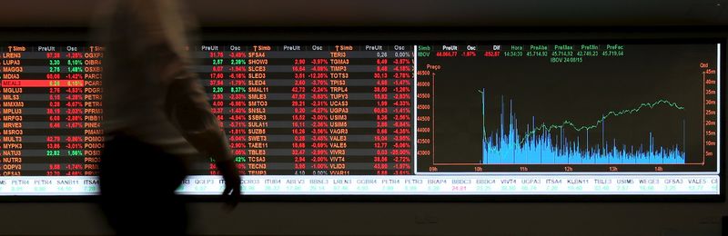 © Reuters. Um homem passa em frente a painel com cotações na BM&F Bovespa