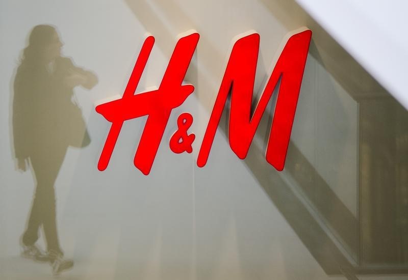 © Reuters. A woman is reflected next to logo of H&M fashion retailer in newly opened Mall of Berlin shopping centre in Berlin