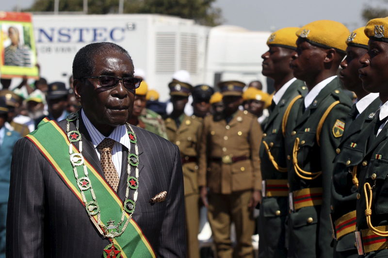 © Reuters. President Mugabe walks past soldiers as he arrives for Zimbabwe's Heroes Day commemorations in Harare