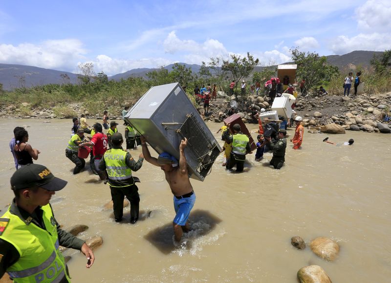 © Reuters. A man carries a refrigerator while crossing the Tachira river border with Venezuela into Colombia, near Villa del Rosario village