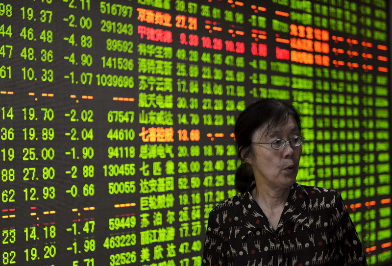 © Reuters. Investor stands in front of an electronic board showing stock information at a brokerage house in Hangzhou