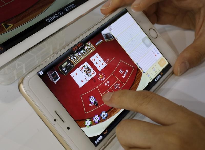 © Reuters. An attendant demonstrates an online baccarat game on a smartphone at the Global Gaming Expo Asia in Macau