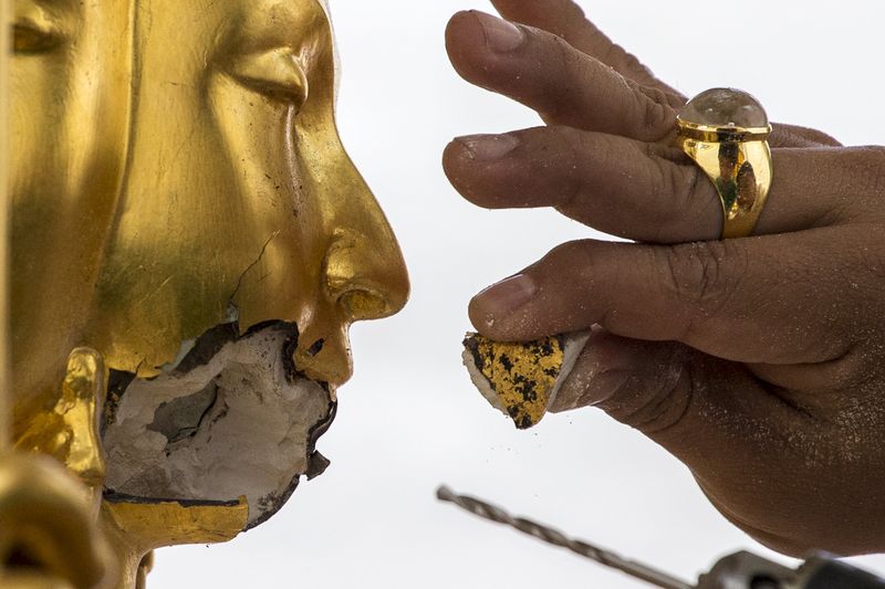 © Reuters. Homem consertando estátua danificada durante explosão em templo em Bangcoc