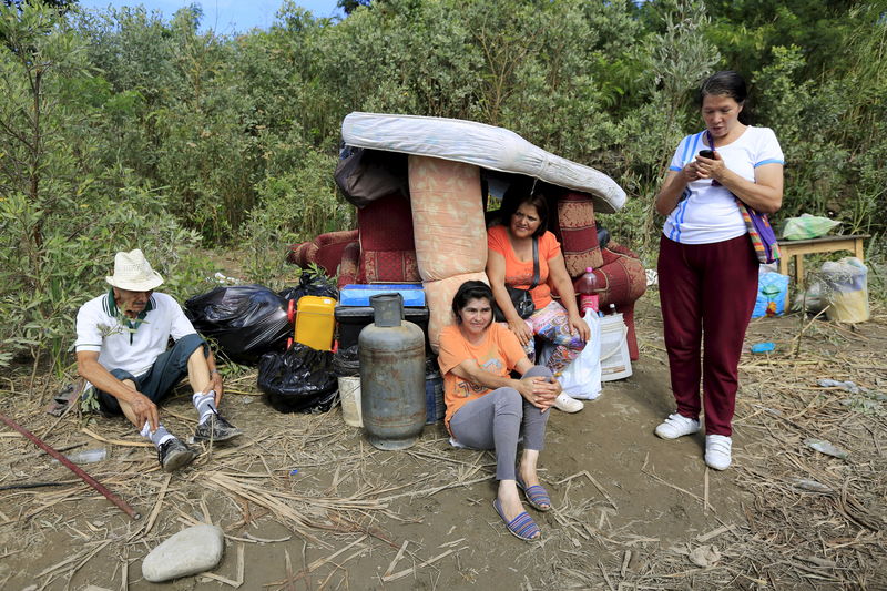 © Reuters. Colombians deported from Venezuela stand with their belongings alongside the Tachira River while waiting to be moved inside Colombia in Villa del Rosario village