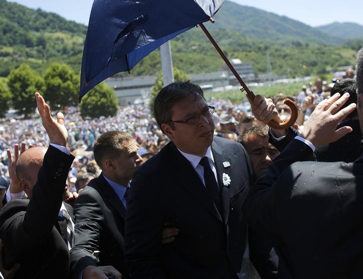 © Reuters. Bodyguards use umbrella to protect Serbia's Prime Minister Vucic during unrest at a ceremony marking the 20th anniversary of the Srebrenica massacre in Potocari