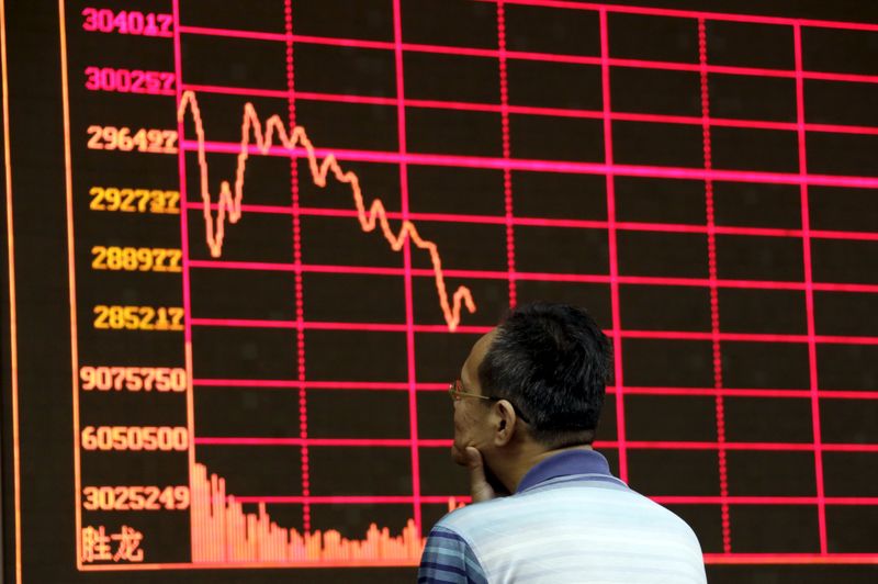 © Reuters. An investor looks at an electronic board showing stock information of Shanghai Stock Exchange Composite Index in Beijing