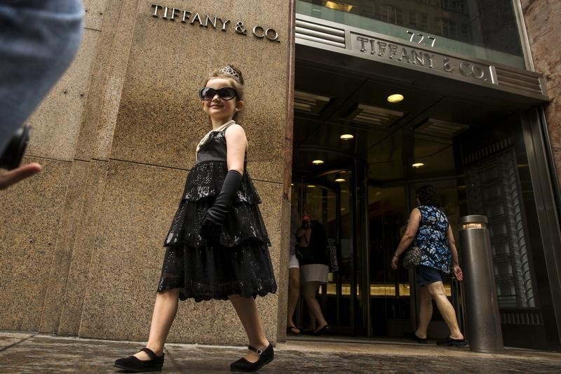 © Reuters. A  young girl dressed as Audrey Hepburn's character in the film "Breakfast at Tiffany's" walks past the Tiffany & Co. store in New York