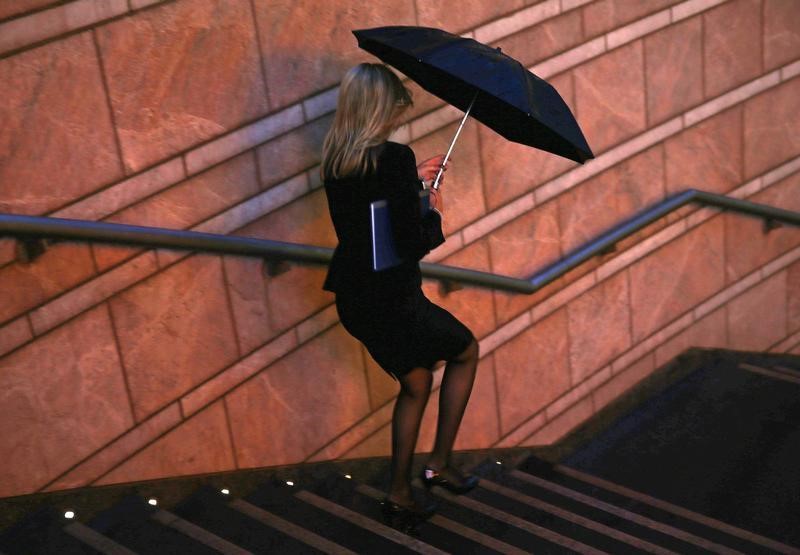 © Reuters. A worker walks in the rain at the Canary Wharf business district in London