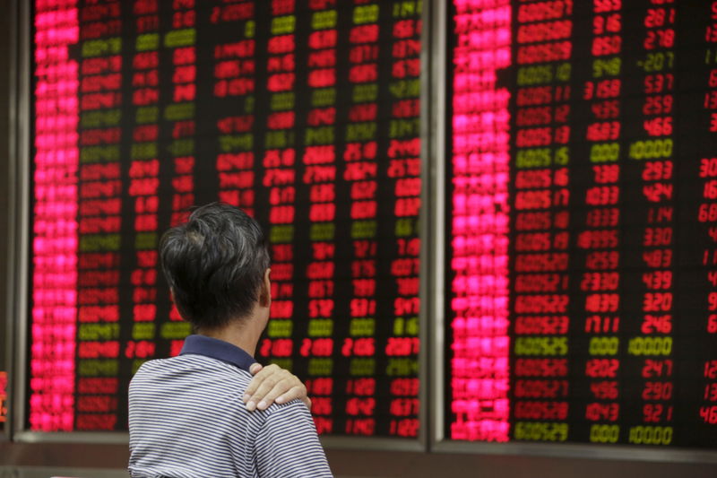 © Reuters. An investor looks at an electronic board at a brokerage house in Beijing