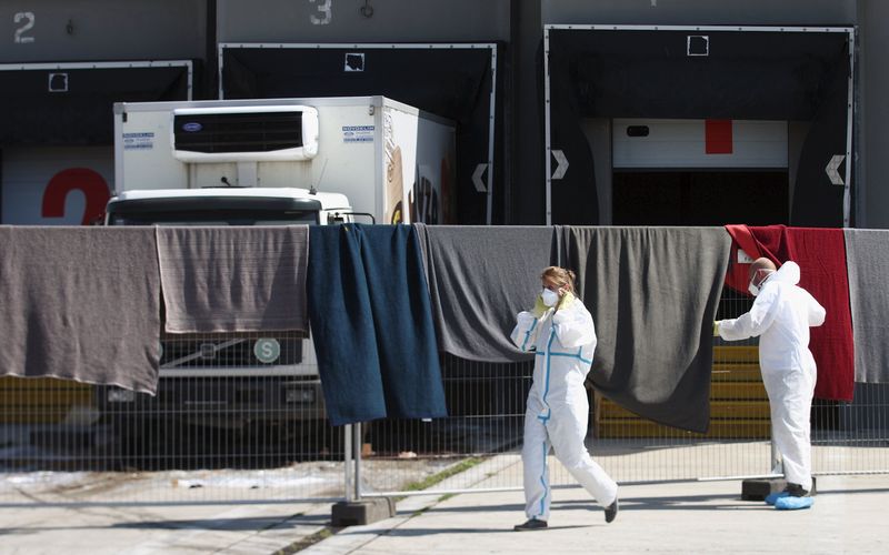 © Reuters. Members of a forensic team walk in front of a truck in which more than 70 bodies were found, at a customs building with refrigeration facilities in the village of Nickelsdorf