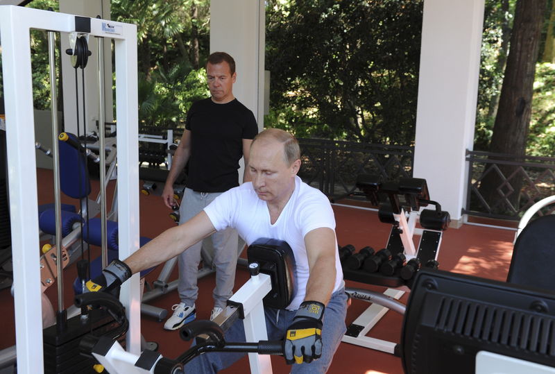 © Reuters. Russian President Putin and Prime Minister Medvedev exercise in a gym at the Bocharov Ruchei state residence in Sochi