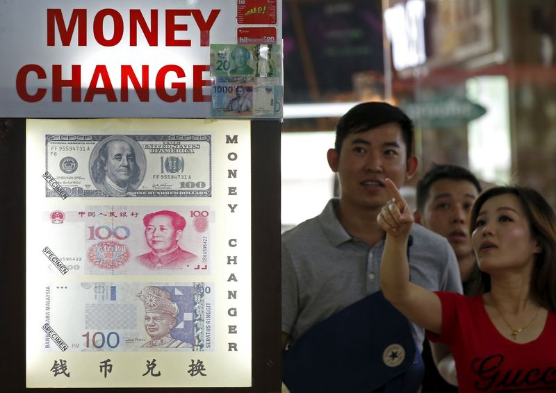 © Reuters. People look at the exchange rate at a Moneychanger displaying posters of U.S. dollars, Chinese Yuan and Malaysia Ringgit in Singapore 
