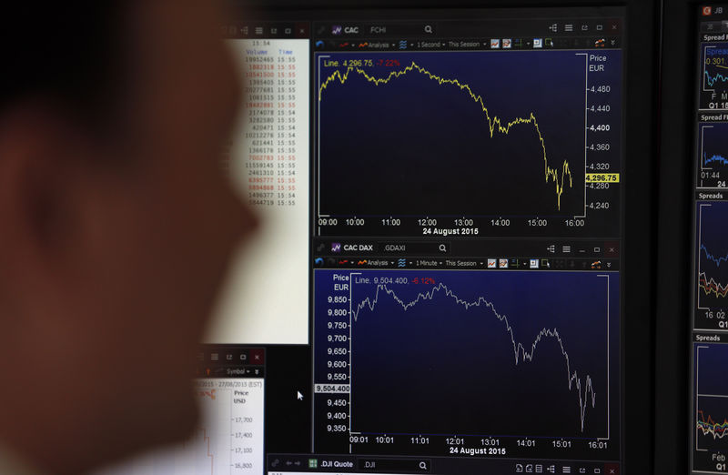 © Reuters. A journalist looks at a screen in this illustration photo that shows graphics representing the losses in the French CAC 40 and German DAX stock indexes in Paris