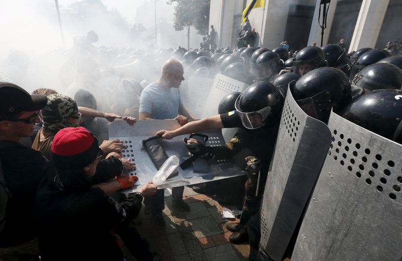 © Reuters. Demonstrators, who are against a constitutional amendment on decentralization, clash with police outside the parliament building in Kiev