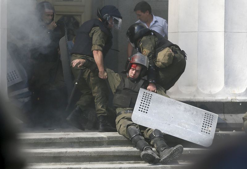 © Reuters. An injured national guard officer is carried away by comrades outside the parliament building in Kiev
