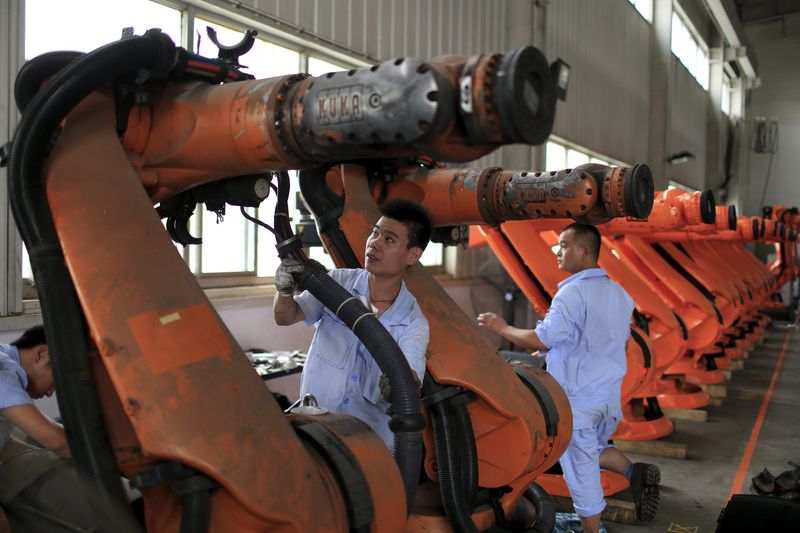 © Reuters. Workers fix second-hand robots in a factory in Shanghai