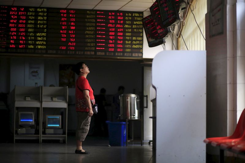 © Reuters. An investor looks at electronic boards showing stock information at a brokerage house in Shanghai