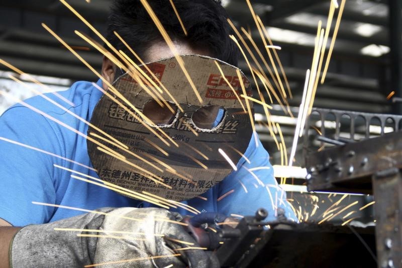 © Reuters. Employee wearing a home-made cardboard mask works inside a bicycle factory in Zaozhuang