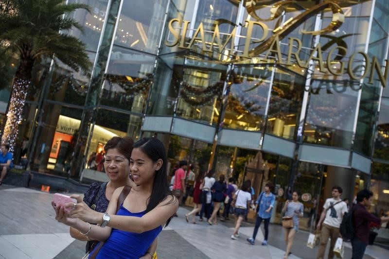 © Reuters. Tourists take a photo of themselves in front of Siam Paragon Department Store in central Bangkok