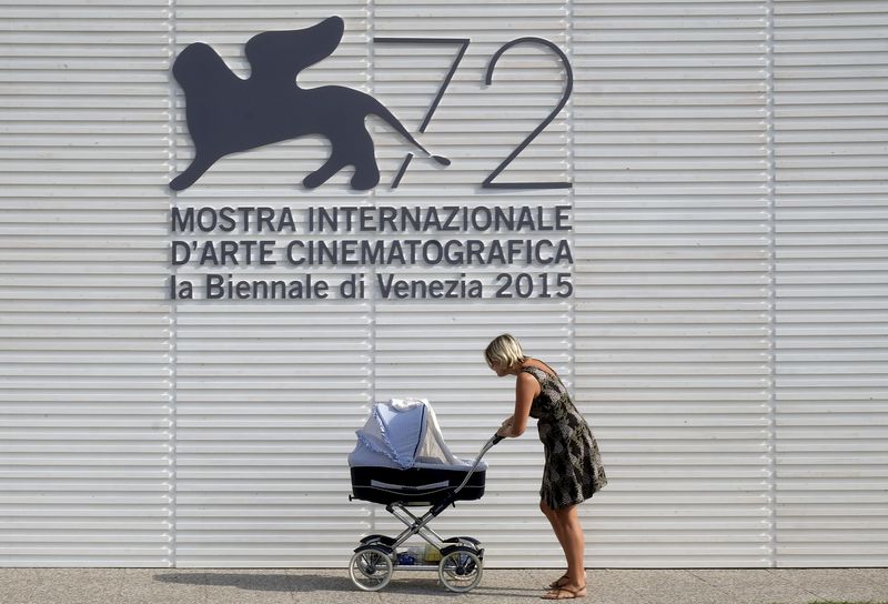 © Reuters. Mulher passa com seu carrinho de bebê em frente ao logo do Festival de Veneza