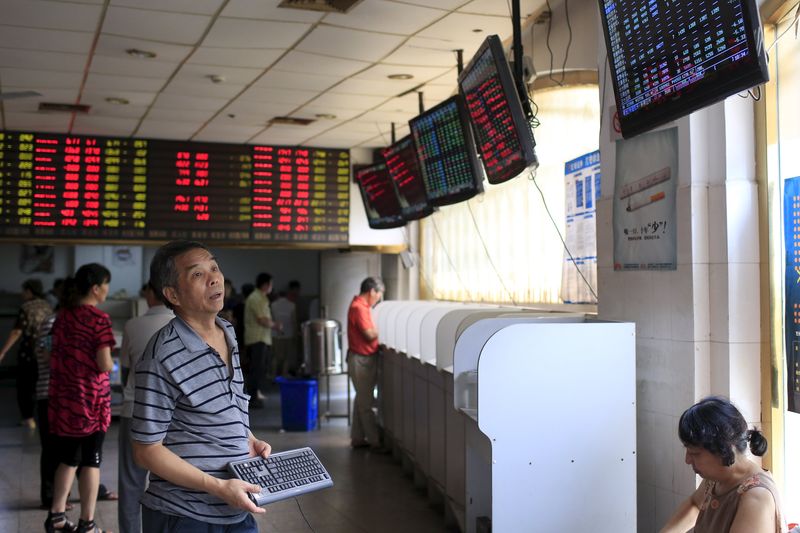 © Reuters. An investor looks at electronic boards showing stock information at a brokerage house in Shanghai