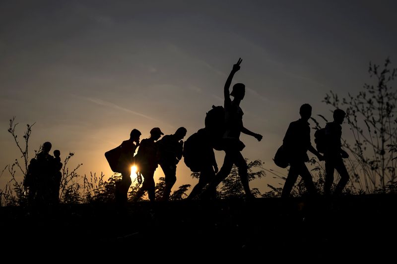 © Reuters. Migrants, hoping to cross into Hungary, walk along a railway track outside the village of Horgos in Serbia, towards the border it shares with Hungary