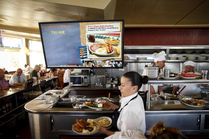 © Reuters. A waitress carries food as customers dine at Norms Diner on La Cienega Boulevard in Los Angeles, California