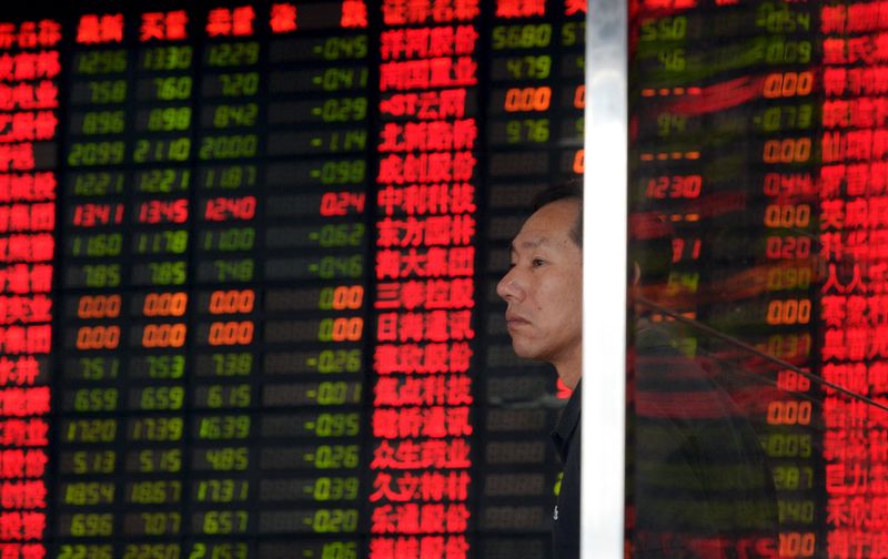 © Reuters. An investor stands in front of an electronic board showing stock information at a brokerage house in Shanghai,