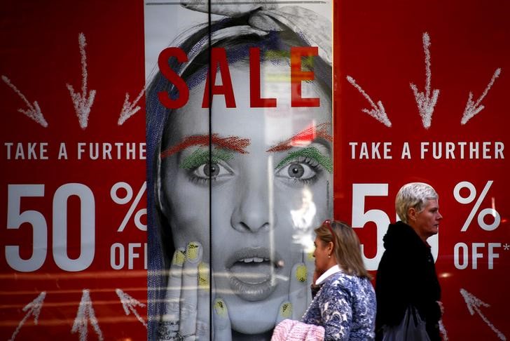 © Reuters. Pedestrians walk past a shop displaying advertising for a sale in central Sydney, Australia