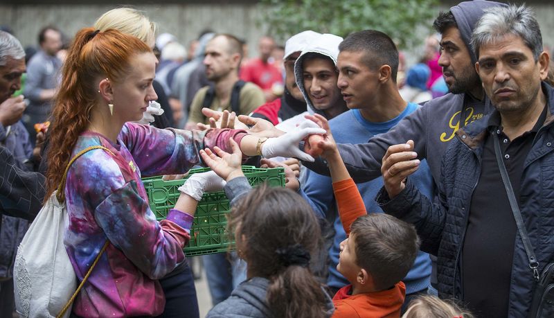 © Reuters. A helper distributes fruit to migrants in front of the State Office for Health and Social Affairs (LaGeSo), in Berlin