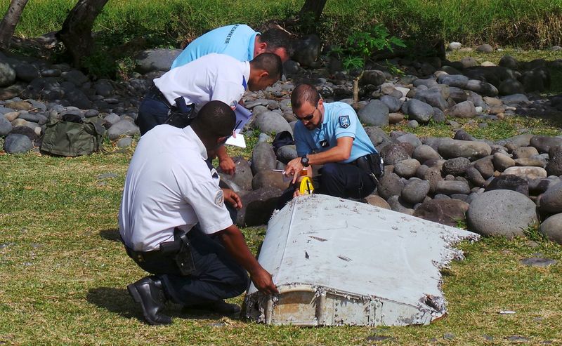 © Reuters. File picture shows French gendarmes and police inspecting a large piece of plane debris which was found on the beach in Saint-Andre on the French Indian Ocean island of La Reunion