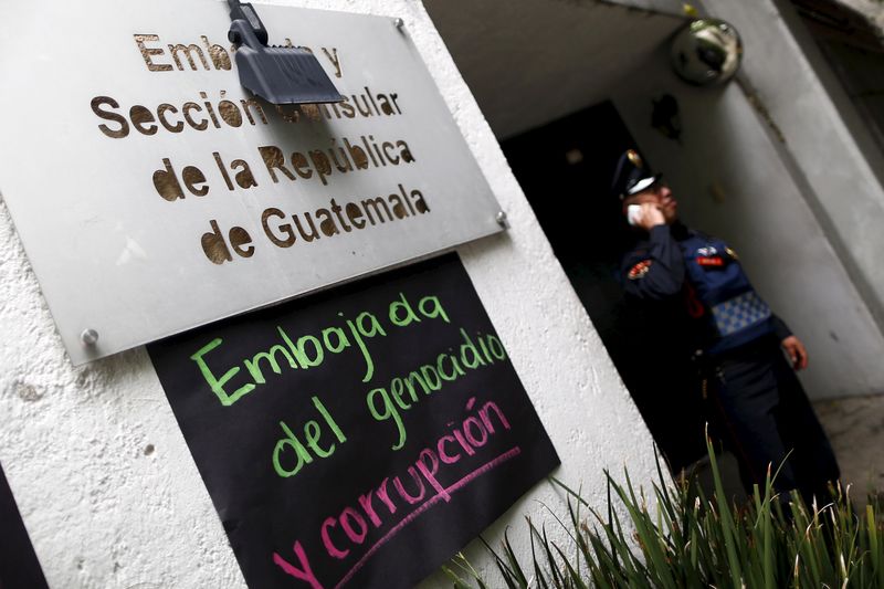 © Reuters. A policeman talks on his cell phone during a demonstration outside the Embassy of Guatemala in Mexico City