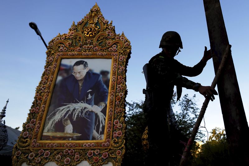 © Reuters. File photo of a soldier climbing a barricade in front of a picture of Thailand's King Bhumibol as his unit dismantles an anti-government encampment in central Bangkok