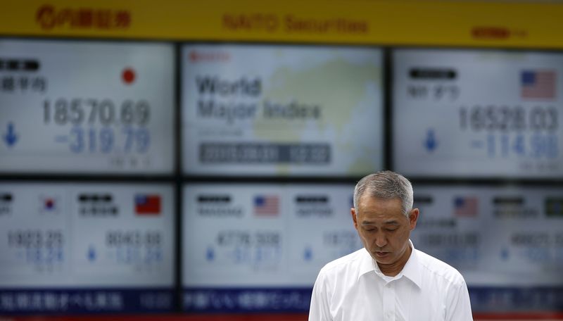 © Reuters. Tokyo, un passante davanti ai tabelloni elettronici di un brokerage con l'andamento dei mercati asiatici