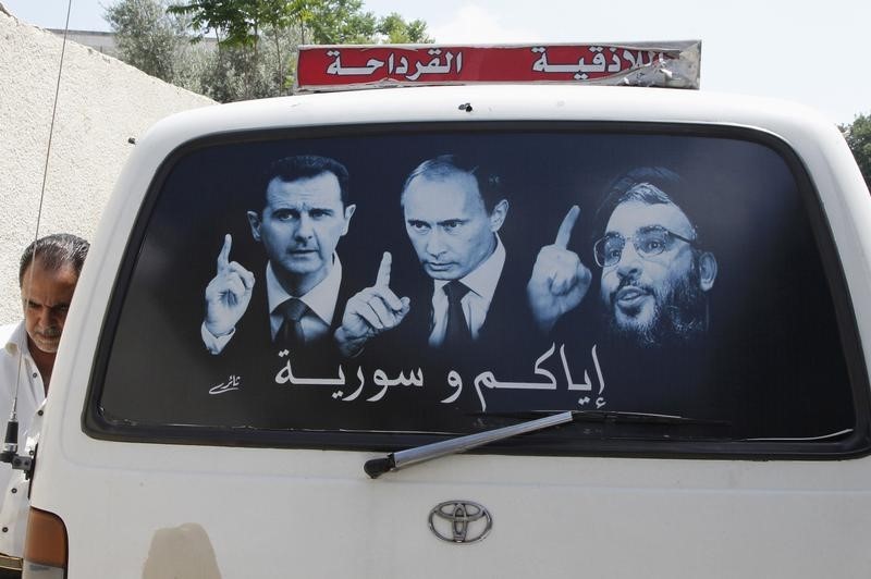 © Reuters. Siria, maggio 2014: un poste elettorale che ritrae il presidente Assad, il leader russo Putin e il capo degli Hezbollah libanesi Nasrallahad su un furgoncino ad al-Qardahah, vicino a Latakia