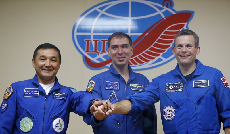 © Reuters. Cosmonauts Aimbetov of Kazakhstan, Volkov of Russia and astronaut Mogensen of Denmark pose behind glass wall after news conference at Baikonur cosmodrome