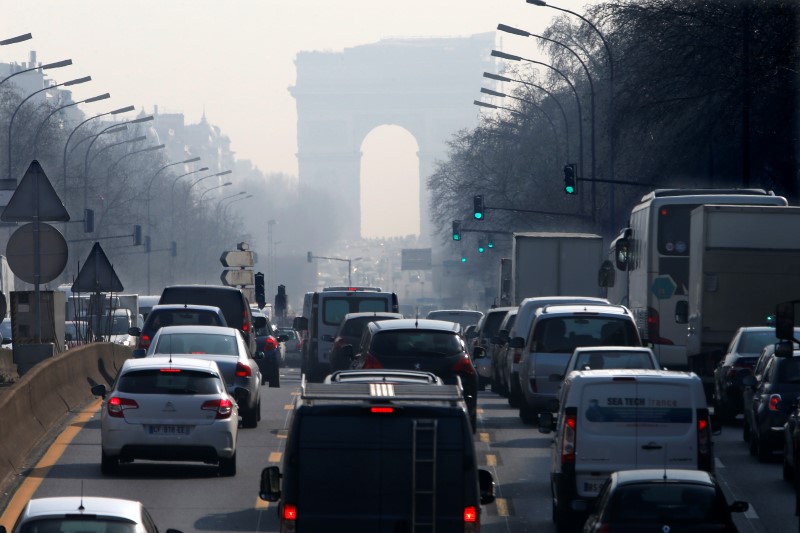 © Reuters. Rush hour traffic fills an avenue leading up to the Arc de Triomphe which seen through a small-particle haze at Neuilly-sur-Seine, Western Paris